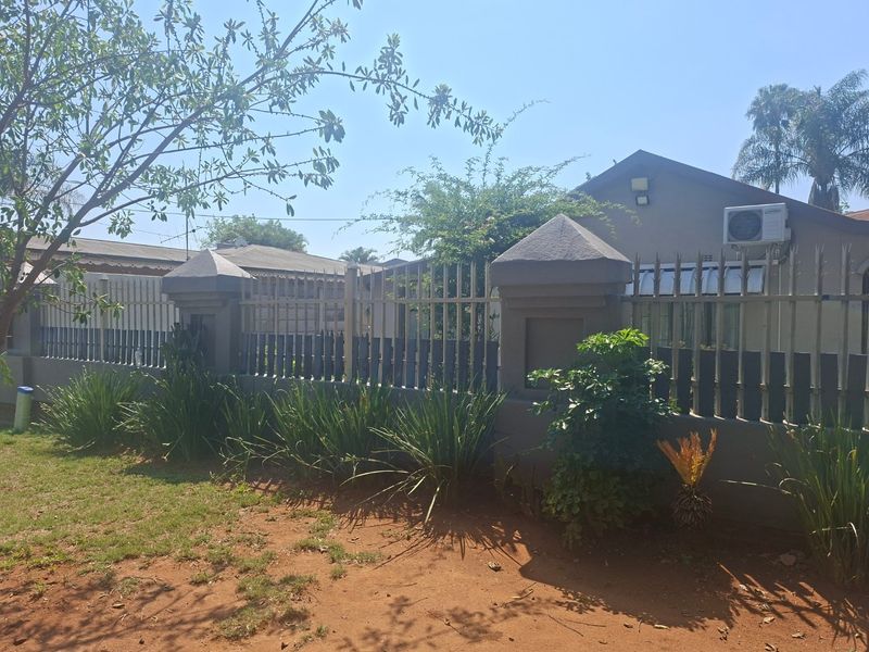 Front view of the property featuring a secure perimeter wall with metal fencing, concrete pillars, and an exterior air conditioning unit.