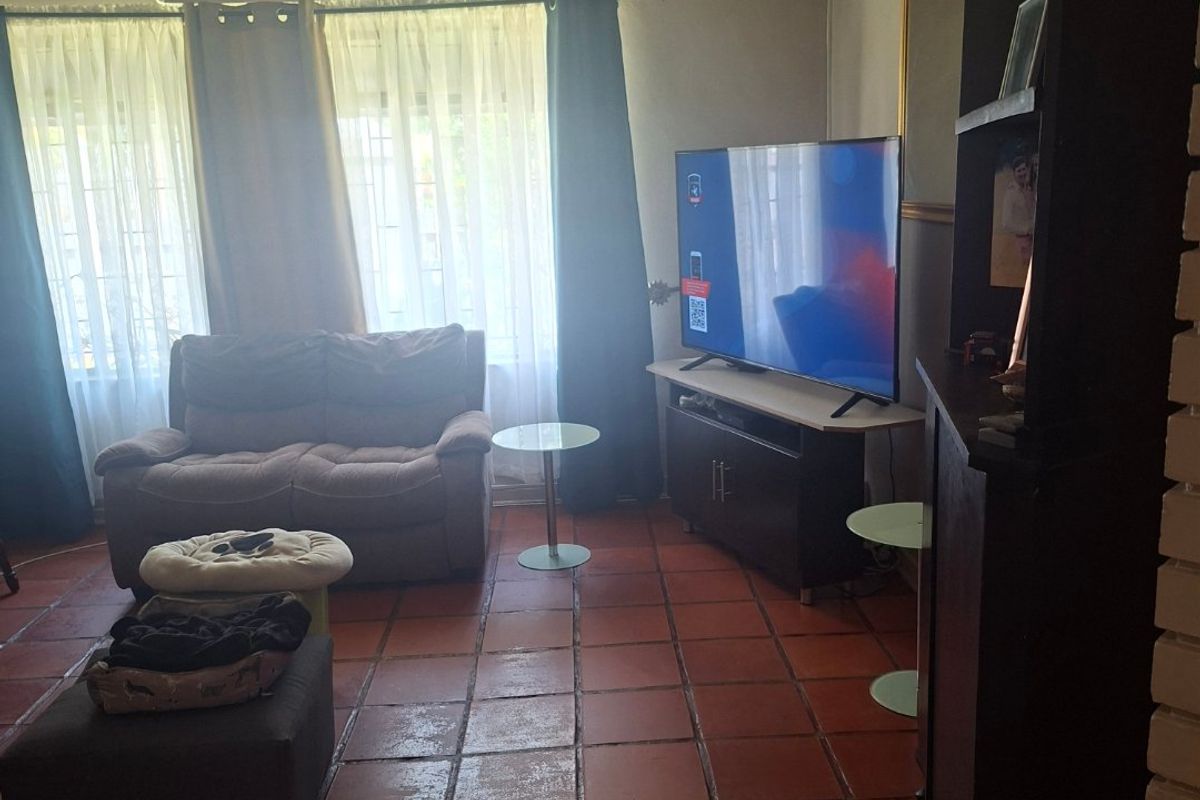 A living room featuring terracotta floor tiles, a timber slat ceiling, and a wall-mounted air conditioning unit.