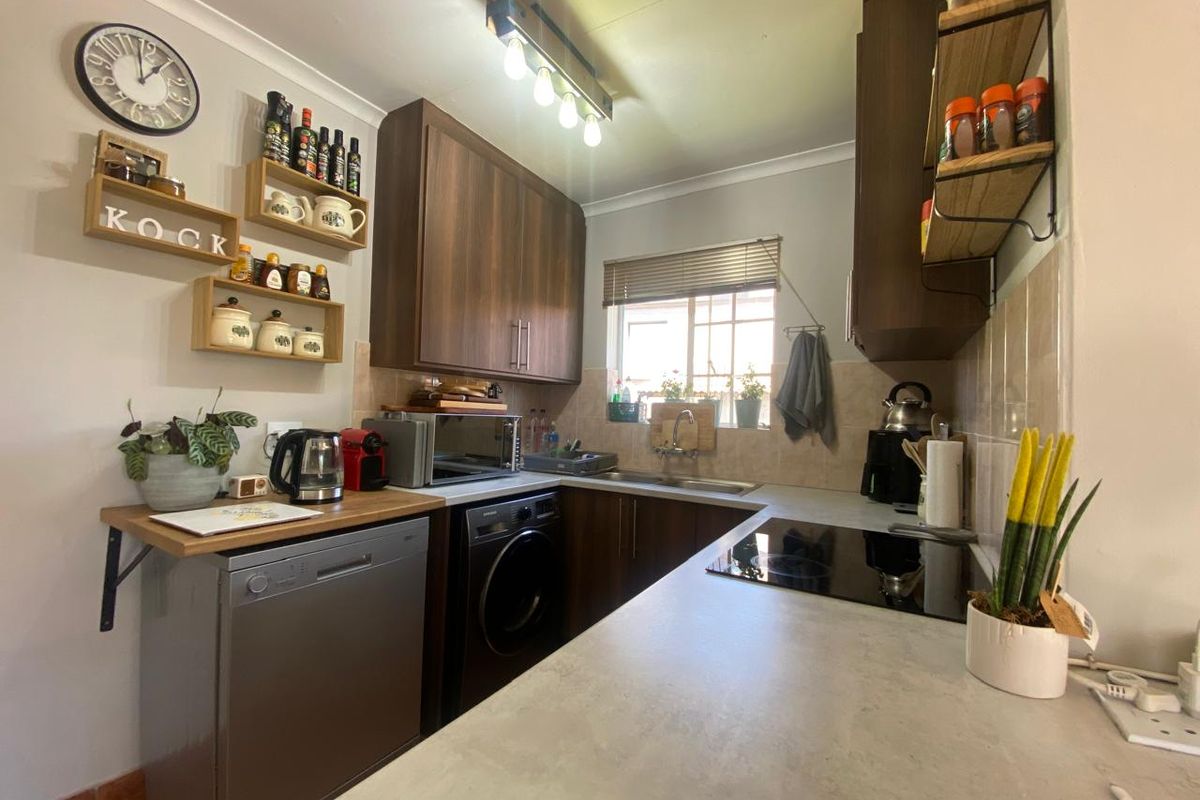 Compact kitchen featuring dark wood cabinetry, laminate countertops, tiled backsplash, and integrated electric hob, providing a functional and efficient workspace.