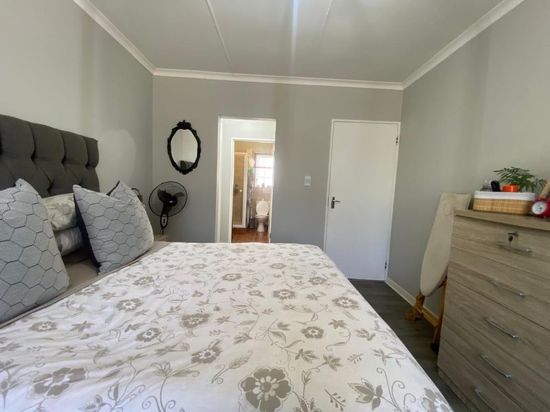 A well-lit bedroom featuring neutral wall tones, laminate flooring, and direct access to an en-suite bathroom.