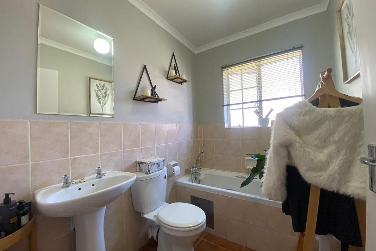 A functional bathroom featuring a pedestal basin, toilet, and bathtub with tiled splashbacks and flooring, offering a clean and practical layout.