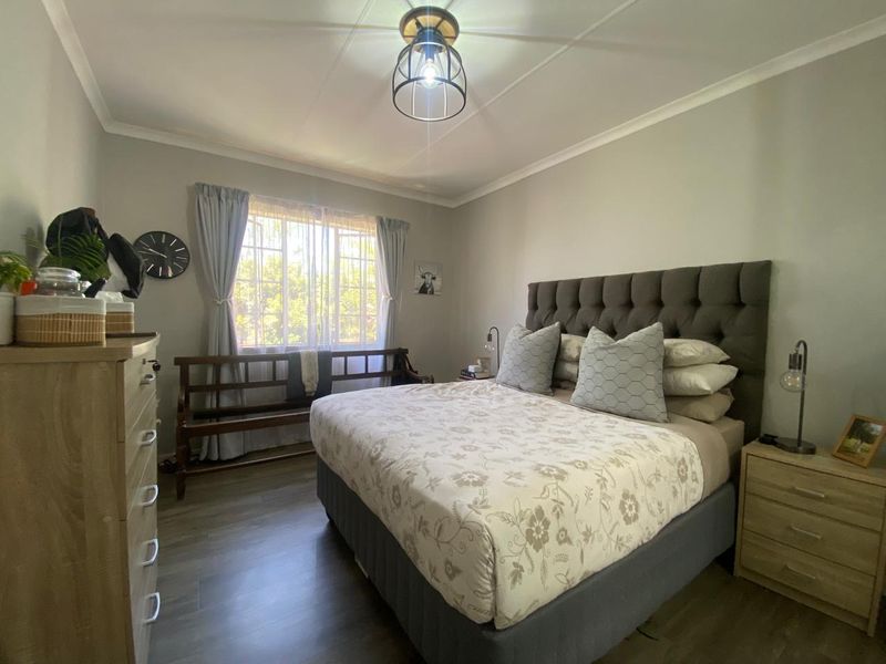 A well-maintained bedroom featuring laminate flooring, neutral wall tones, and a central ceiling light fixture, providing a comfortable and functional living space.