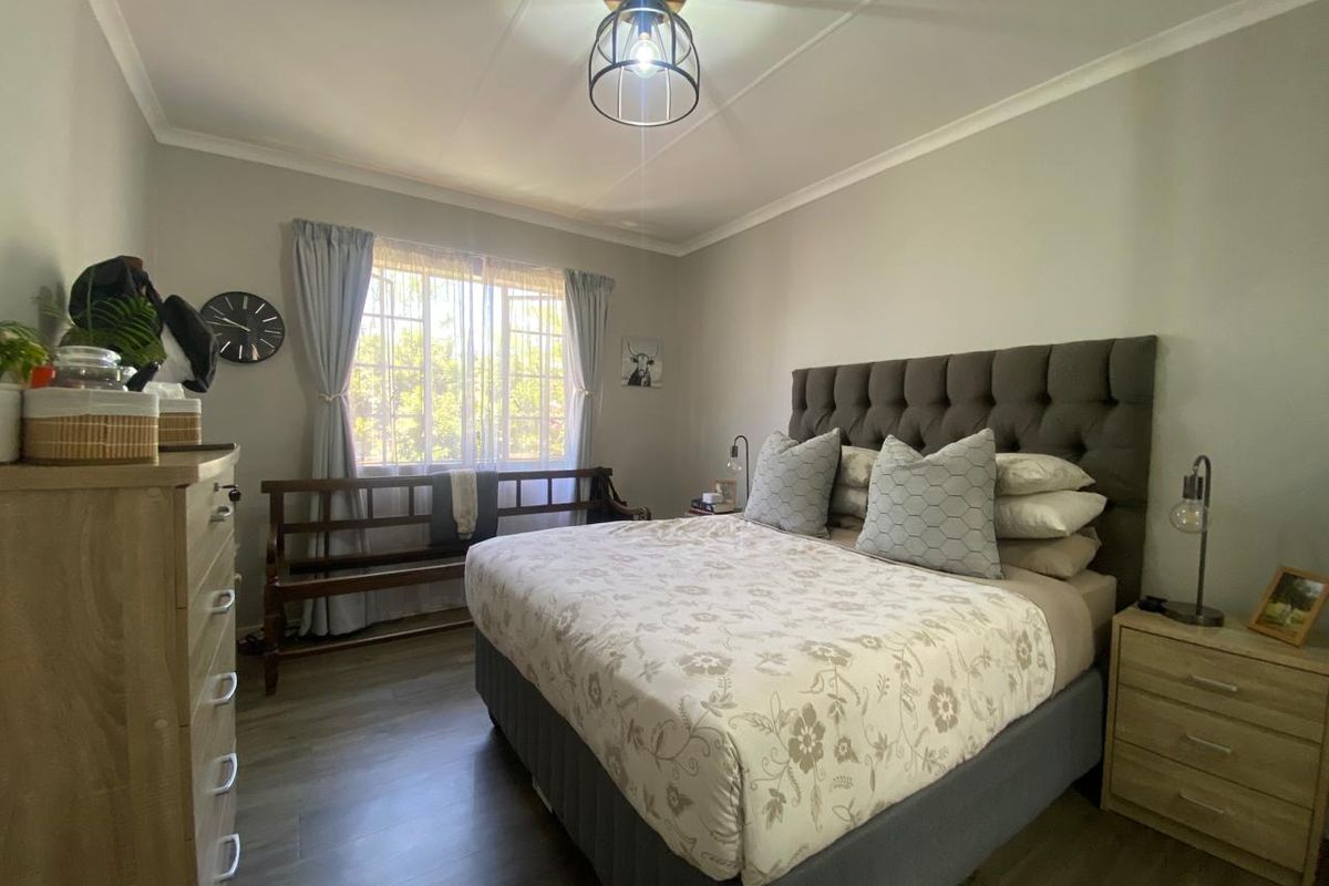 A well-maintained bedroom featuring laminate flooring, neutral wall tones, and a central ceiling light fixture, providing a comfortable and functional living space.