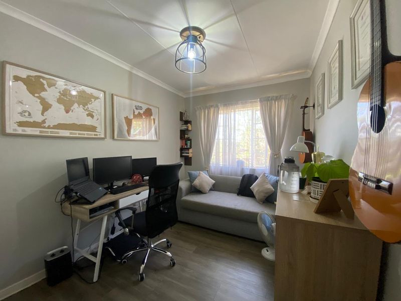 A functional home office space featuring laminate flooring, neutral wall tones, and a window providing natural light.