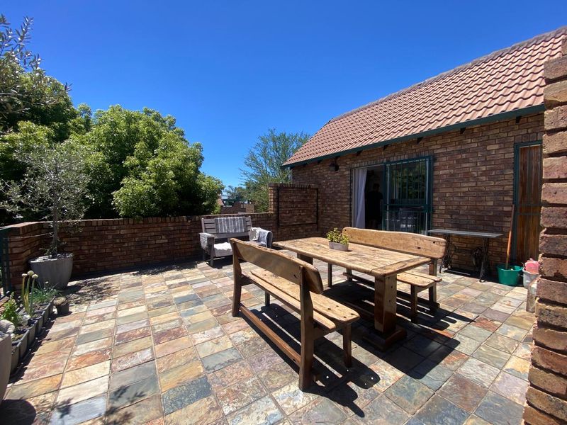 A spacious outdoor patio area featuring durable tiled flooring and brick wall construction, providing a functional space for outdoor dining and relaxation.