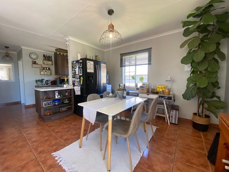 Open plan dining and kitchen area featuring terracotta floor tiles, modern pendant lighting, and functional kitchen cabinetry with a central island.