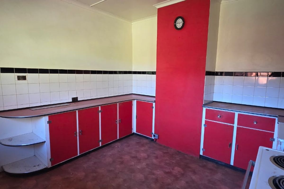 A dated kitchen featuring red and white cabinetry, tiled backsplash, and an electric stove, offering a blank canvas for modern renovation.
