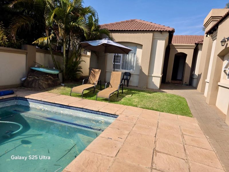 Outdoor pool area featuring a paved patio, swimming pool with tiled coping, and a landscaped garden space adjacent to the main house structure.
