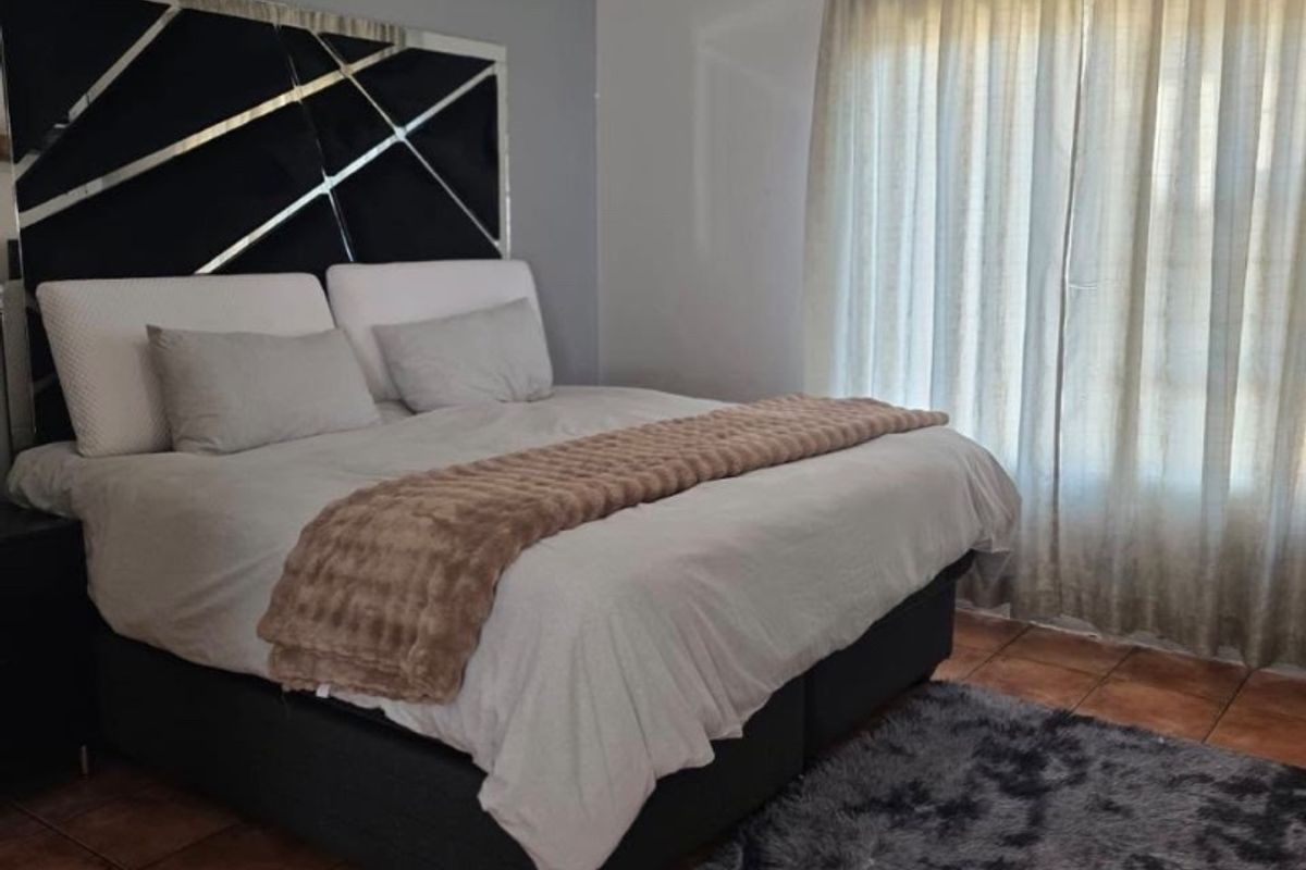 A well-lit bedroom featuring tiled flooring, a ceiling fan, and neutral wall tones, providing a comfortable and functional sleeping space.