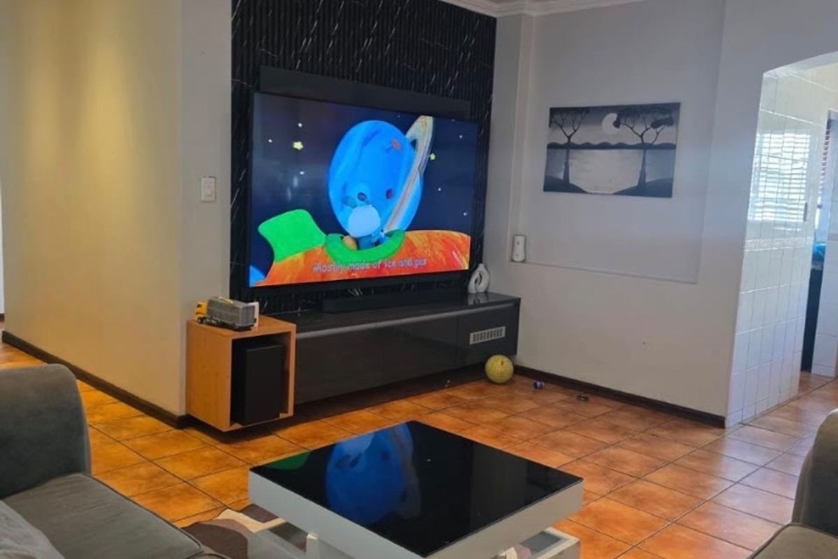 A comfortable living room featuring tiled flooring, recessed downlighting, and a modern feature wall with integrated media space.