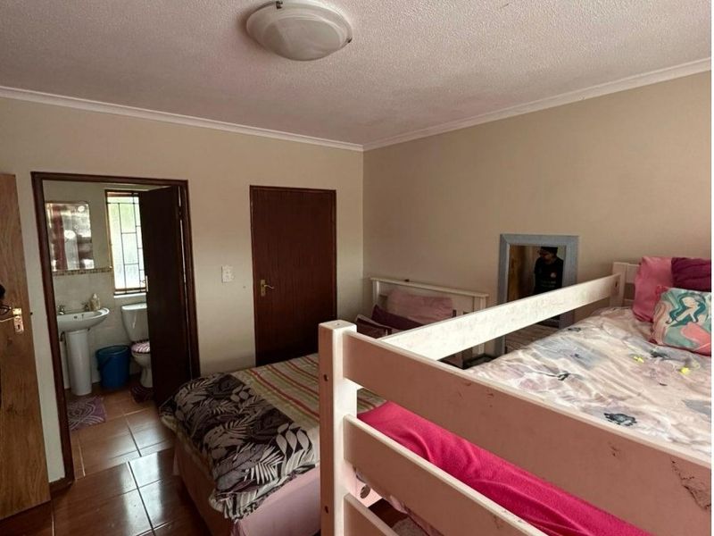A bedroom featuring tiled flooring and an en-suite bathroom, providing a functional layout with standard finishes.