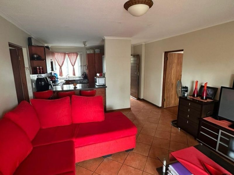 Open plan living area featuring tiled flooring and a functional kitchen space with built-in cabinetry and countertops.