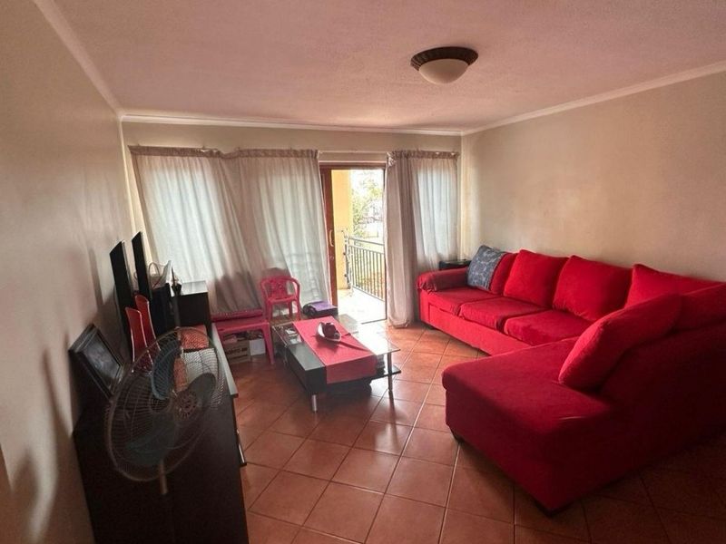 A living room featuring tiled flooring and a sliding glass door providing access to an outdoor balcony area.