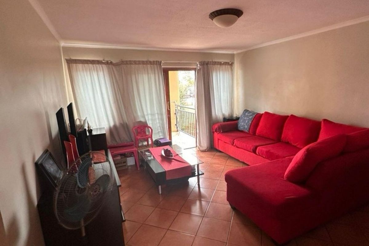 A living room featuring tiled flooring and a sliding glass door providing access to an outdoor balcony area.