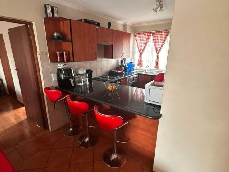 A functional kitchen featuring dark wood cabinetry, granite countertops, a breakfast bar, and tiled flooring, offering a practical layout for daily use.