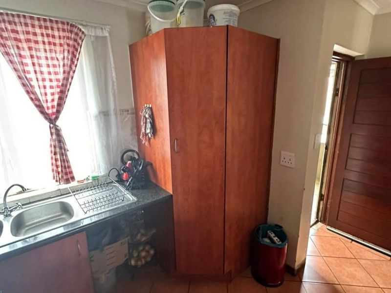 A functional kitchen area featuring built-in cabinetry, a stainless steel sink with granite countertops, and durable tiled flooring.