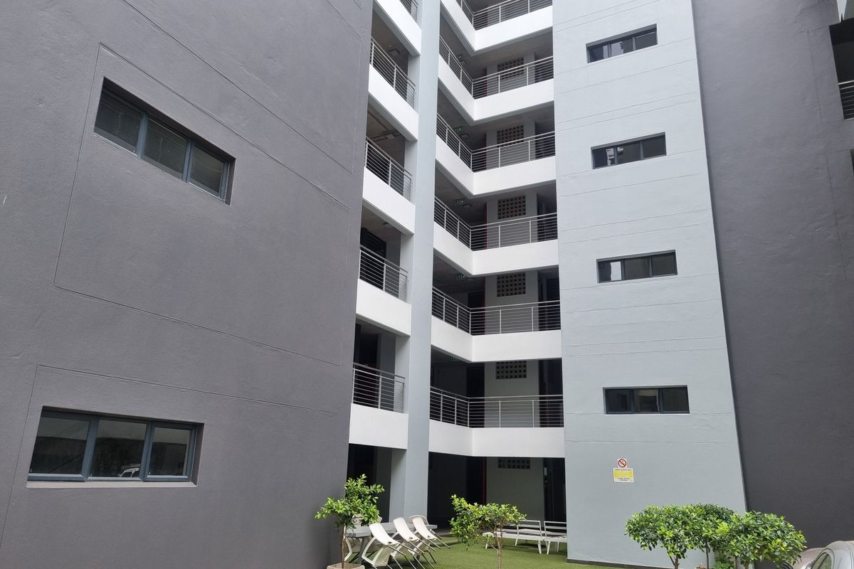 A view of the multi-story apartment building facade featuring modern grey and white exterior finishes with metal balcony railings.