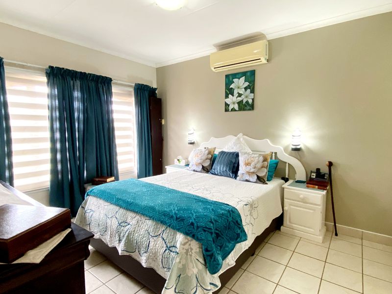 A well-lit bedroom featuring tiled flooring, a built-in wardrobe, and a wall-mounted split-system air conditioning unit.