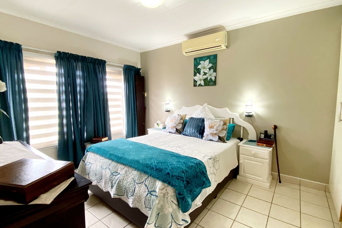 A well-lit bedroom featuring tiled flooring, a built-in wardrobe, and a wall-mounted split-system air conditioning unit.