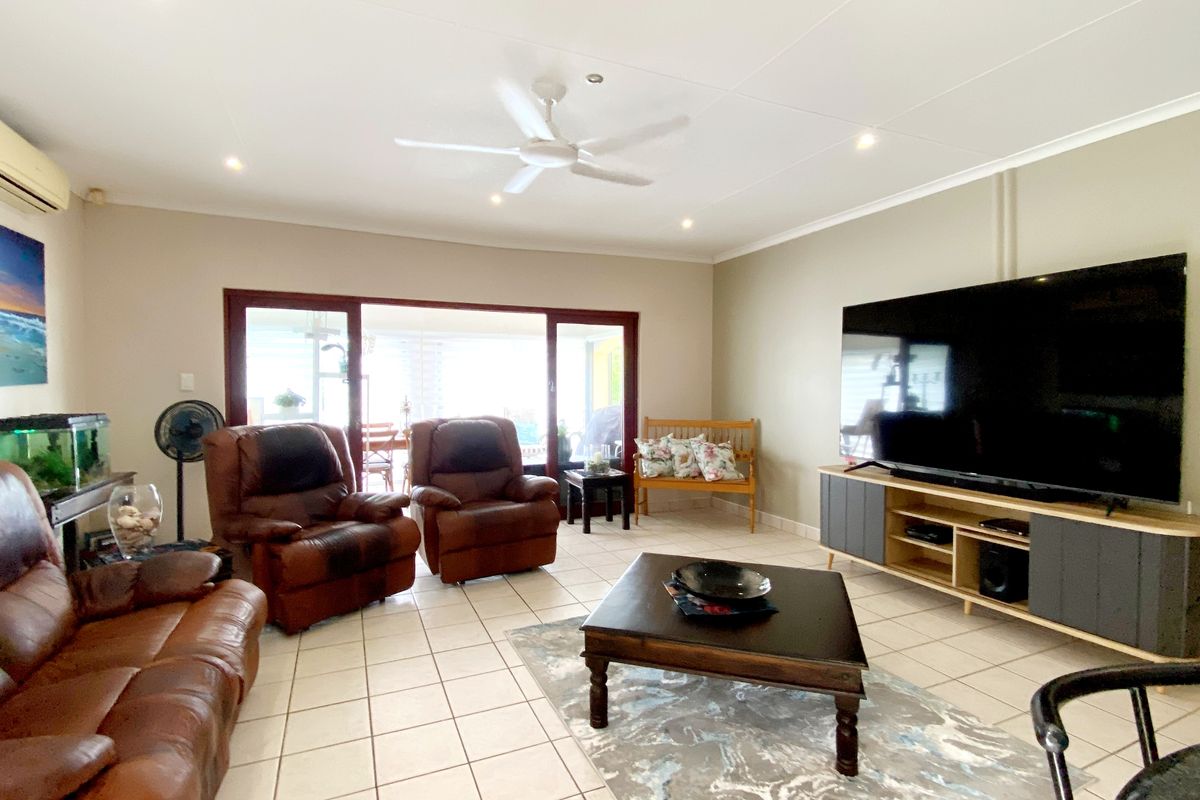Spacious living room featuring tiled flooring, recessed lighting, a ceiling fan, and large sliding glass doors providing access to the outdoor area.