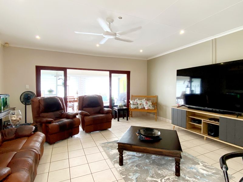 Spacious living room featuring tiled flooring, recessed lighting, a ceiling fan, and large sliding glass doors providing access to the outdoor area.
