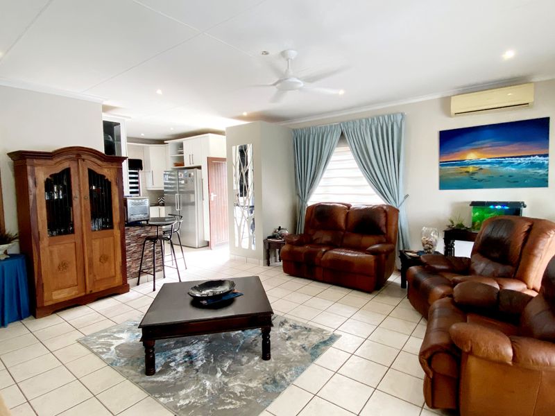 Spacious open-plan living area featuring tiled floors, recessed lighting, a ceiling fan, and an integrated kitchen with breakfast bar and air conditioning.