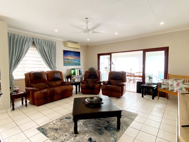 Spacious living room featuring tiled flooring, recessed lighting, a ceiling fan, and large sliding glass doors providing access to the outdoor patio area.