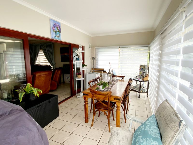 Enclosed patio area featuring tiled flooring, large sliding glass doors connecting to the living space, and adjustable roller blinds for natural light control.