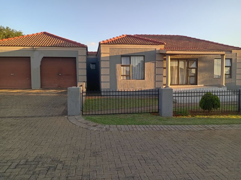 Front elevation of a townhouse featuring a double garage, paved driveway, and a covered entrance porch with concrete pillars.