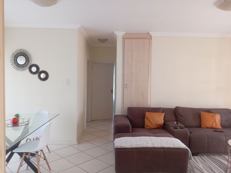 A living area featuring tiled flooring, neutral walls, and a built-in storage cupboard, providing a functional and well-maintained space.
