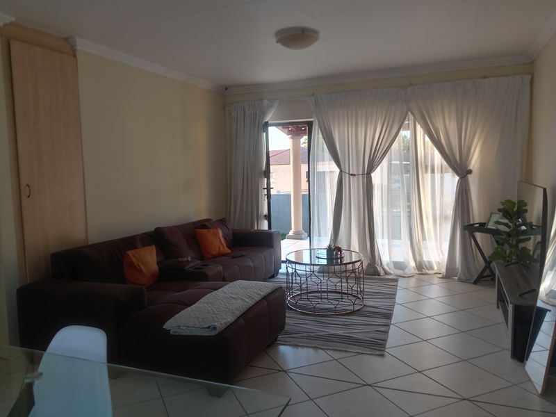 A living room featuring tiled flooring, a built-in cupboard, and a sliding glass door providing access to an outdoor patio area.