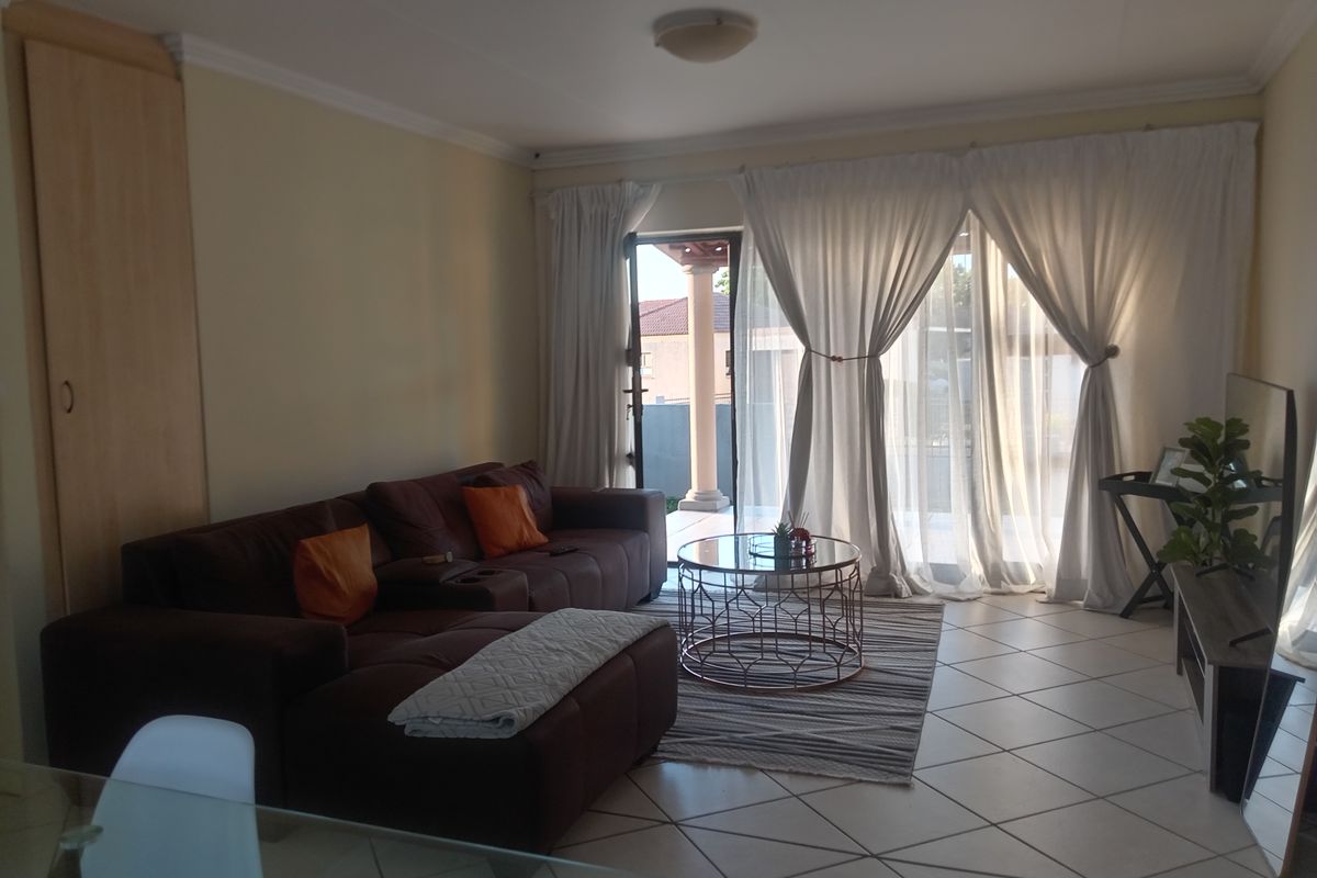 A living room featuring tiled flooring, a built-in cupboard, and a sliding glass door providing access to an outdoor patio area.