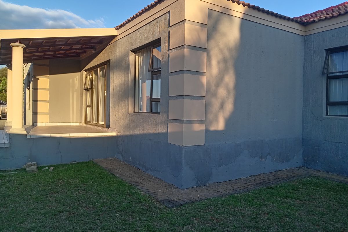 Rear view of the townhouse featuring a covered patio, sliding glass doors, and a paved walkway surrounding the exterior walls.