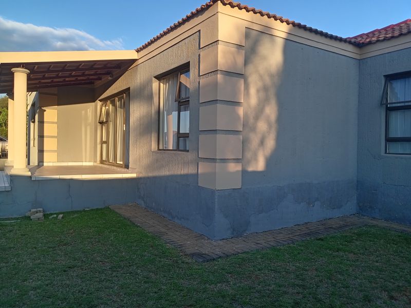 Rear view of the townhouse featuring a covered patio, sliding glass doors, and a paved walkway surrounding the exterior walls.
