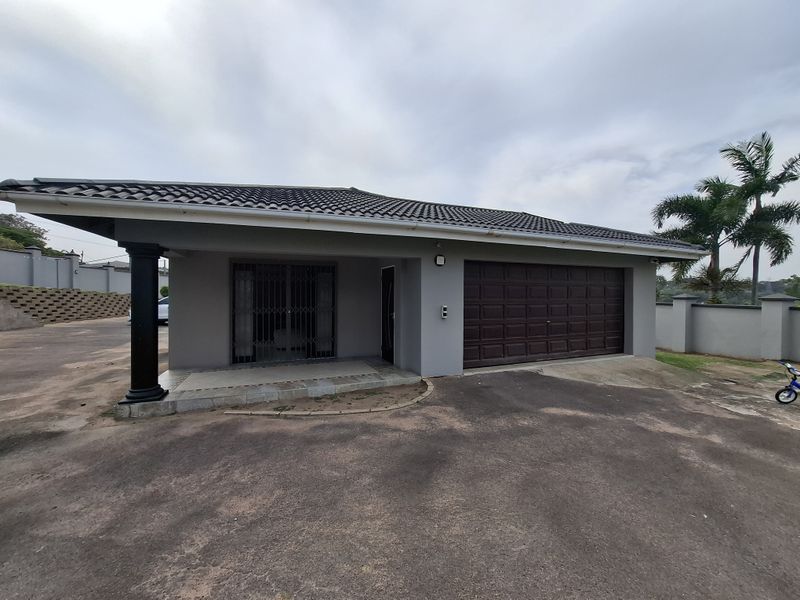 Front elevation of a single-story house featuring a double garage, covered entrance porch, and perimeter walling on a paved driveway.