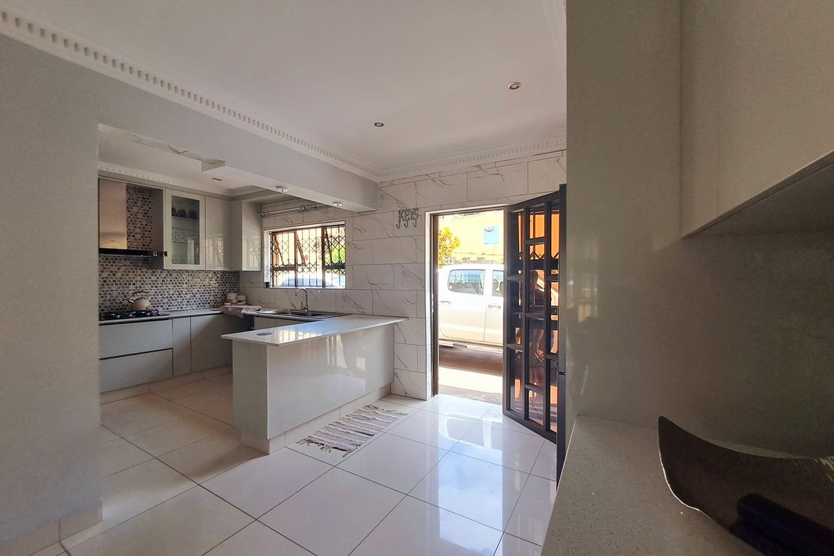 Modern kitchen featuring sleek cabinetry, stone countertops, a breakfast bar, and a gas hob, with direct access to the exterior.