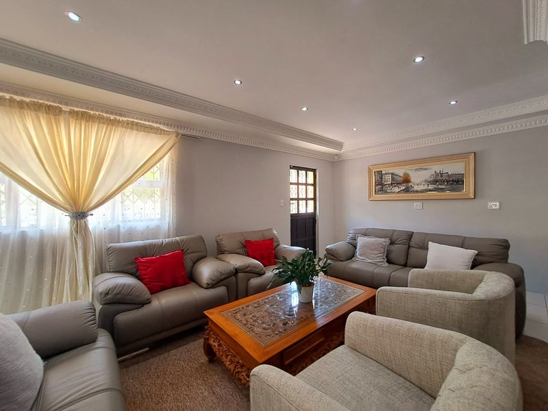 A comfortable living room featuring decorative ceiling cornicing, recessed downlighting, and a secure entrance door.