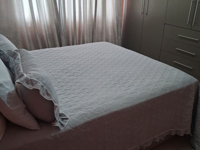 A well-maintained bedroom featuring neutral tiled flooring and integrated built-in cupboards for ample storage.
