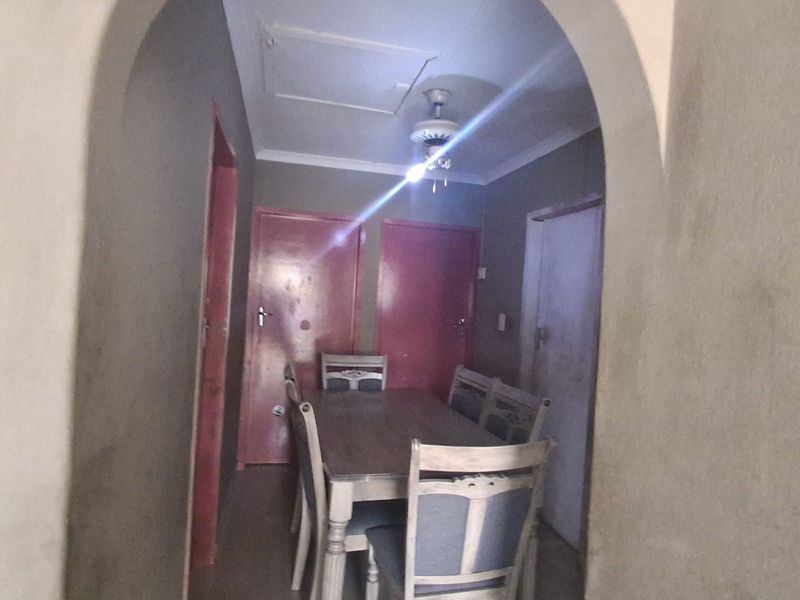 A dining area featuring an arched entryway, ceiling fan, and multiple interior doors, requiring cosmetic updates to improve the overall aesthetic.
