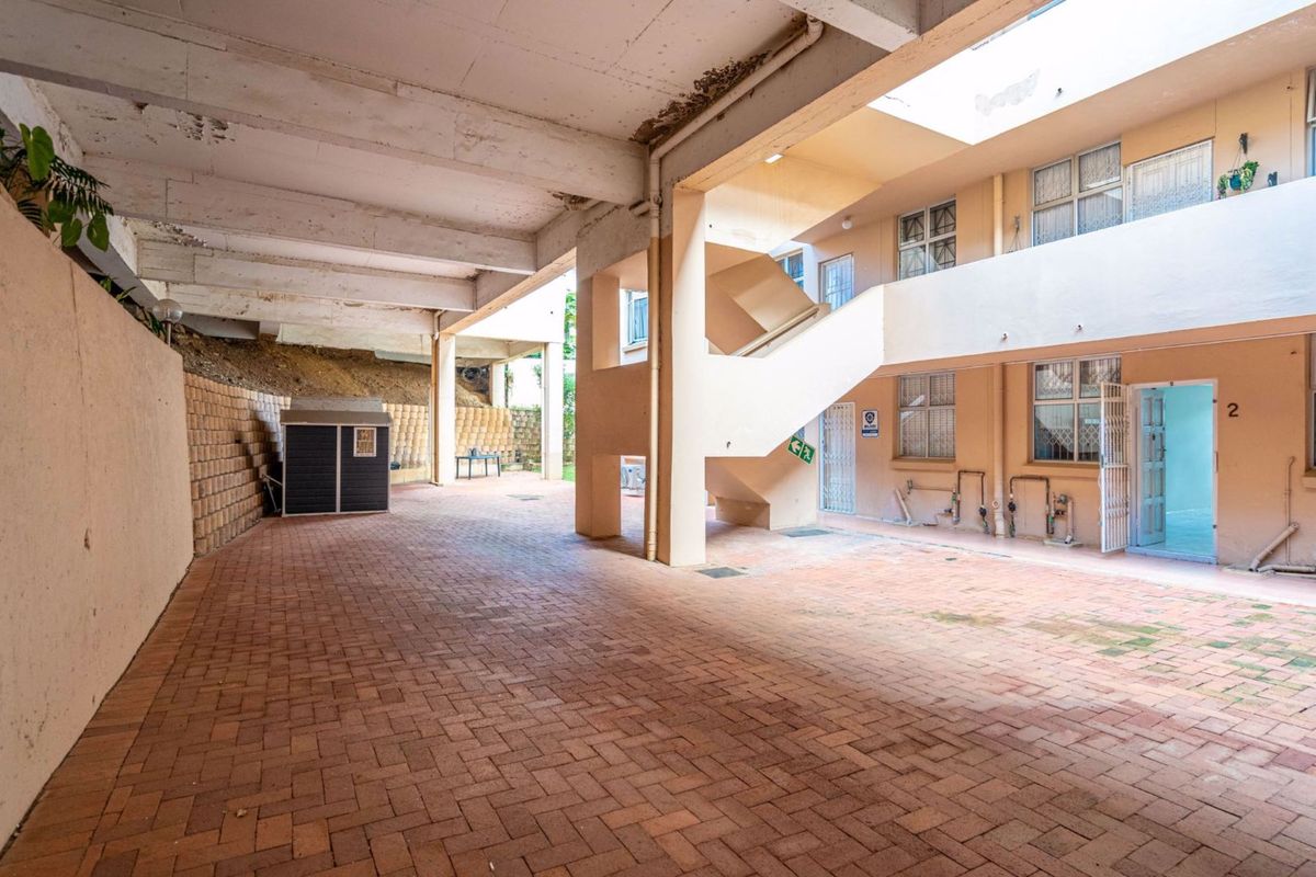 A communal outdoor courtyard area featuring brick paving, a concrete staircase, and access to residential units.