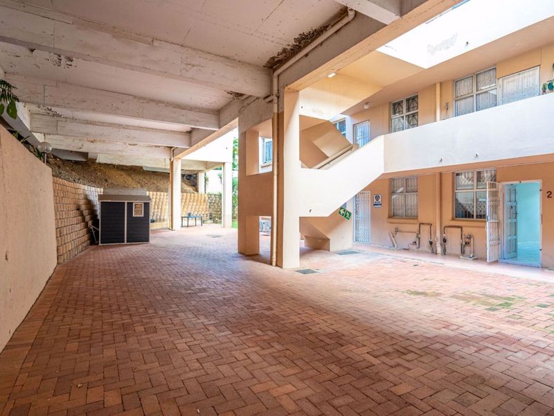 A communal outdoor courtyard area featuring brick paving, a concrete staircase, and access to residential units.