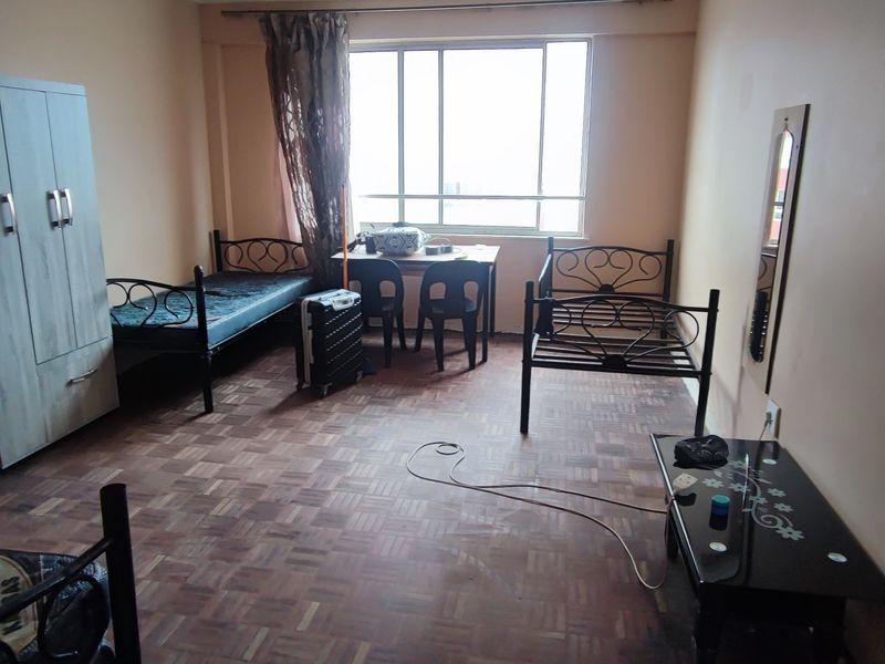 A bedroom featuring parquet flooring and a large window, providing natural light. The space requires cosmetic updates to improve its overall condition.