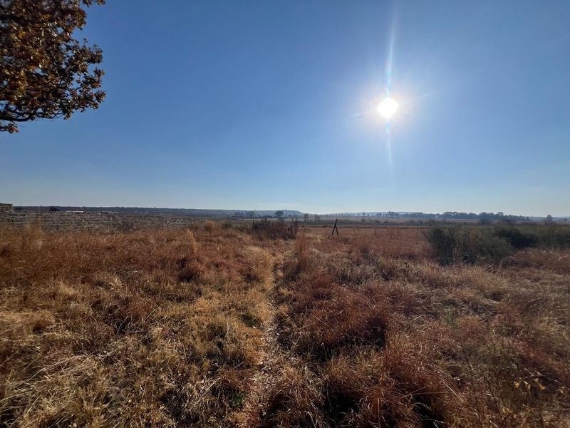 Expansive open farmland view featuring dry grass fields and distant horizon under a clear blue sky.