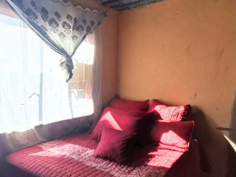 A bedroom featuring natural light from a window, with walls requiring finishing and painting to improve the overall aesthetic and condition.