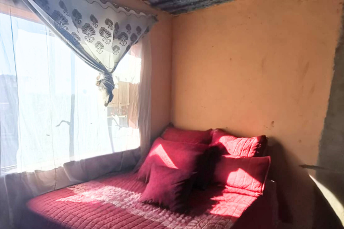A bedroom featuring natural light from a window, with walls requiring finishing and painting to improve the overall aesthetic and condition.