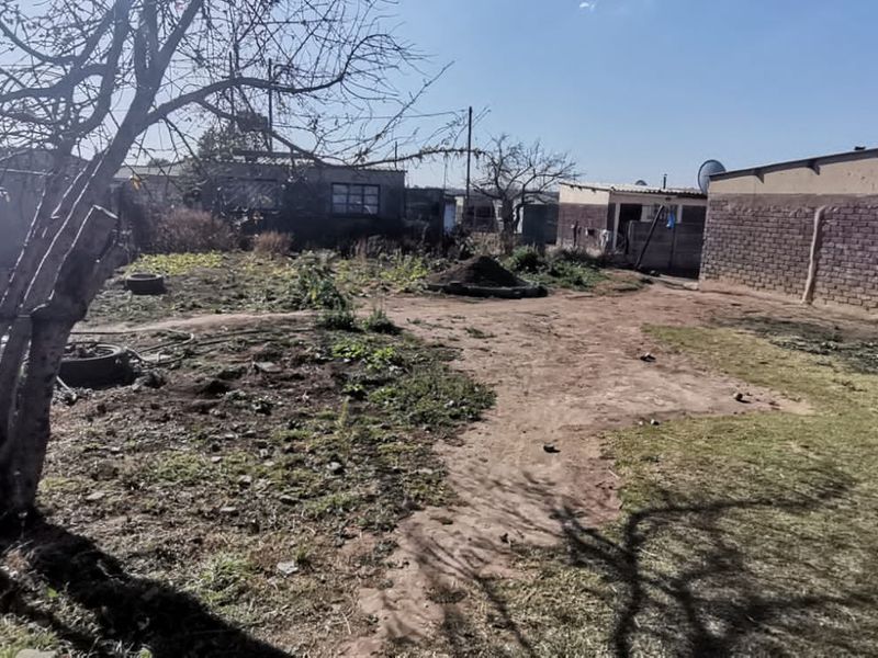 A spacious rear yard area featuring exposed brick structures and boundary walls, offering significant potential for landscaping and outdoor development.