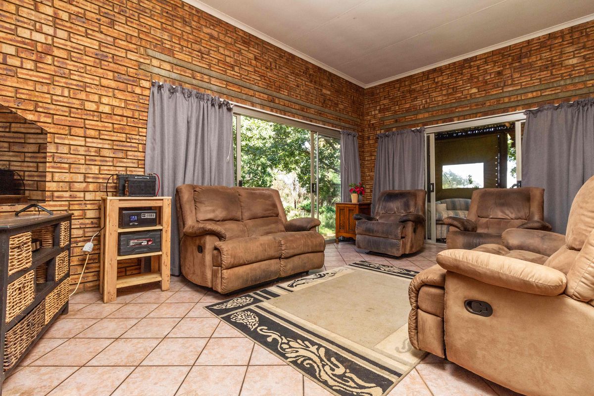 Spacious living room featuring exposed brick walls, ceramic floor tiles, and large sliding glass doors providing access to the outdoor area.