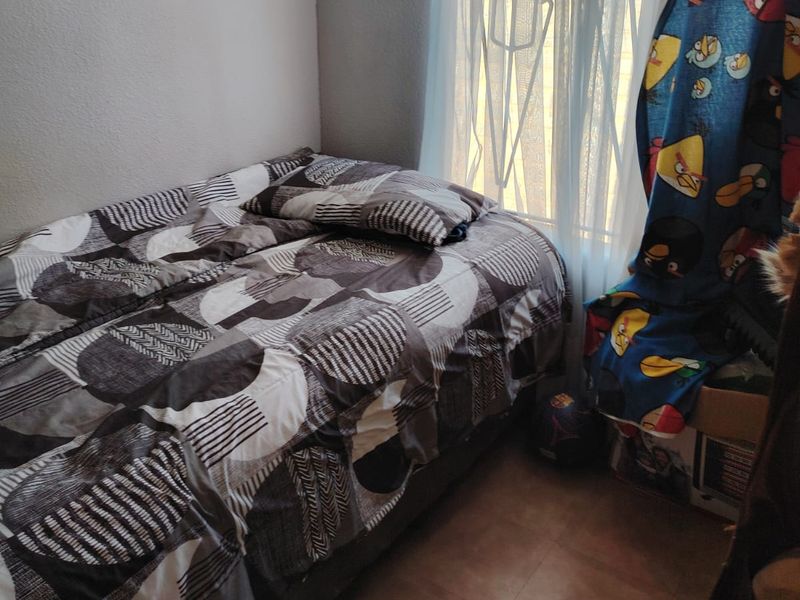 A compact bedroom featuring tiled flooring and a window fitted with a security gate.