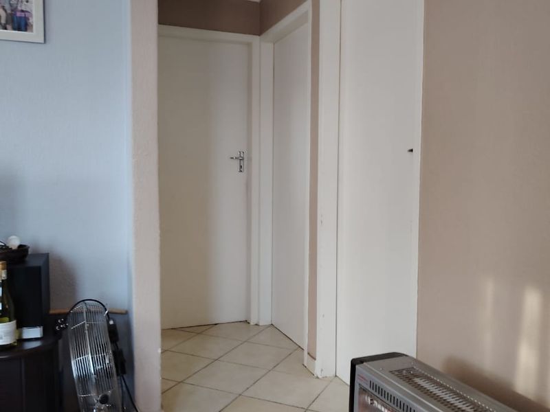 A functional hallway featuring tiled flooring and a ceiling access hatch, providing access to multiple internal rooms.