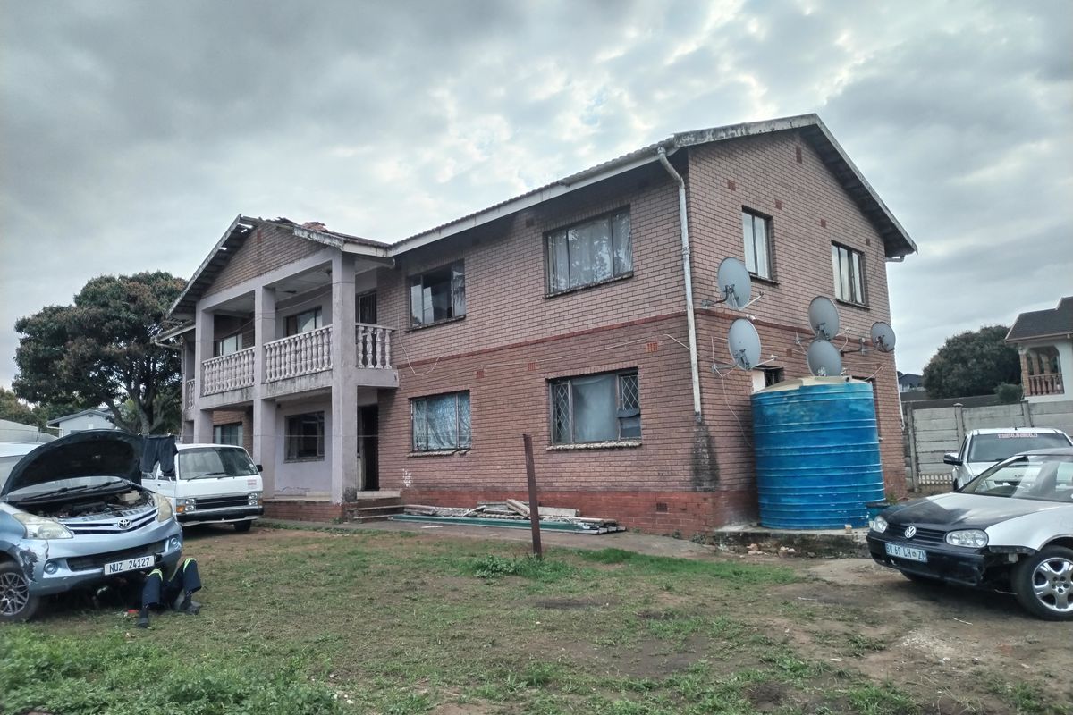 Two-story brick residential property featuring a front balcony with balustrade and an external water storage tank.